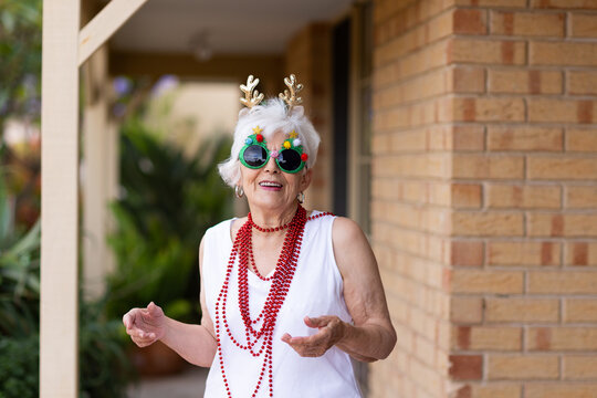 happy senior citizen dressed up for Christmas in sparkly glasses and beads