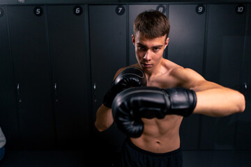 portrait of a young boy boxer in boxing gloves practicing his punches in the gym before training