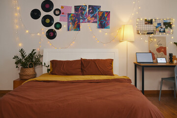 Decorated bedroom of teenager with string lights, placards and vinyl records on walls