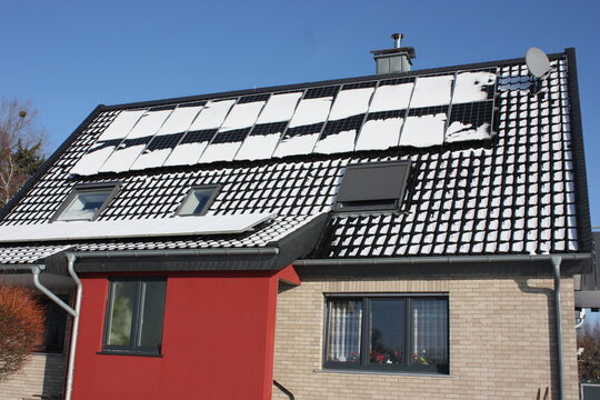 Eine schneebedeckte Photovoltaikanlage auf einem Haus in Lippetal B&uuml;ninghausen, bei blauem Himmel