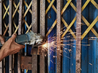 Man cuts the lock or padlock on old steel metal shutter and folding door gate with an angle...