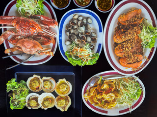 Top view of variety Seafood party table with scallop, cockle, crab, clams, shrimps, crayfish on black background. Seafood platter on black wooden table. Assortment of different seafood with vegetables
