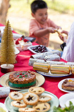 a table laden with christmas food with child blurred in background pulling Christmas cracker