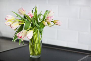 Pink tulips bouquet in glass vase on the kitchen