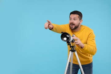 Happy astronomer with telescope pointing at something on light blue background. Space for text