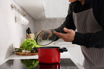 Man cooking and smelling dish on cooktop in kitchen, closeup