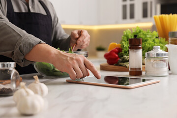 Man using tablet while cooking at countertop in kitchen, closeup
