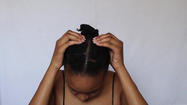 Young African Woman undoing her natural 4c hair on a white background