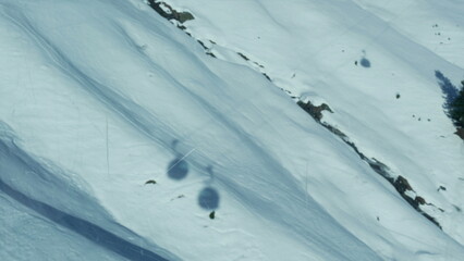 Multiple ski lifts transportation shadows seen from high above in mountain covered with snow during...
