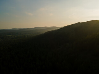 A beautiful evening sunrise landscape. Aerial view beautiful high mountains and green pine forest at sunset. Nature background. Photo from the drone.