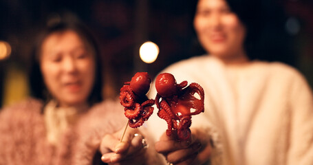 Women, Japan and travel street food at night for octopus delicacy, culture or traditional. Female...
