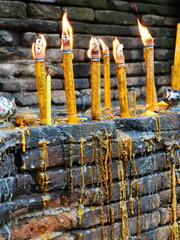 brennende buddhistische Kerzen und mit Wachs getropfte Mauer