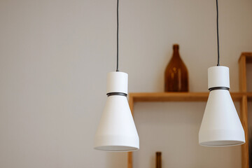 Two modern white pendant lights illuminate the minimalist interior. Concept for stylish home decor...