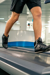 close-up of the legs of an athlete running on a treadmill in a gym during cardio training