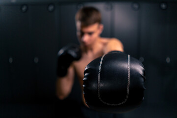 close-up kickboxer in boxing gloves practices punches in the locker room in the gym training