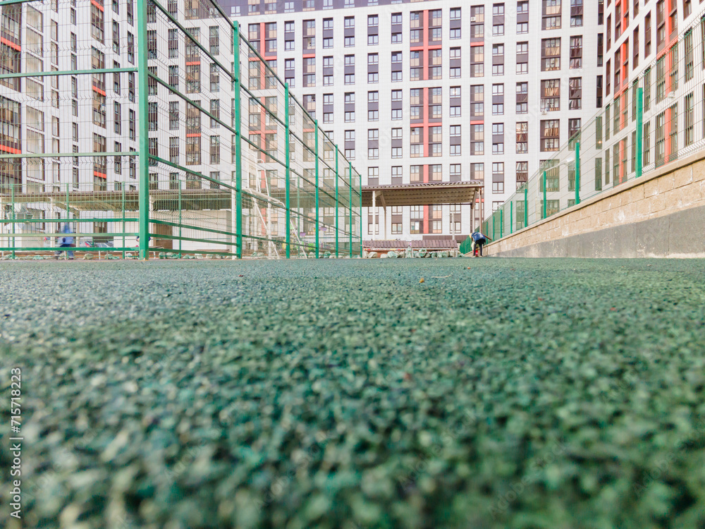 Poster the courtyard of a multi-storey building, a playground covered with a green rubber modular coating n