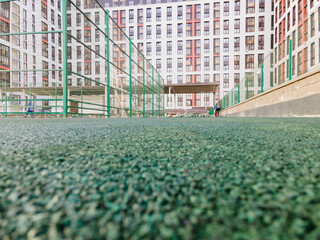 The courtyard of a multi-storey building, a Playground covered with a green rubber modular coating...