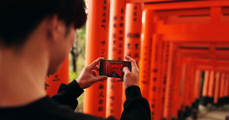 Phone, man and picture of torii gates on vacation, holiday trip or travel for tourism. Smartphone,...