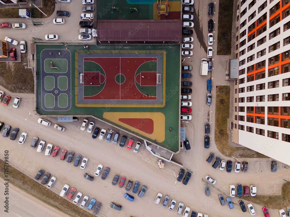 Poster top view of a football field, parking with cars, a playground covered with a green rubber modular co