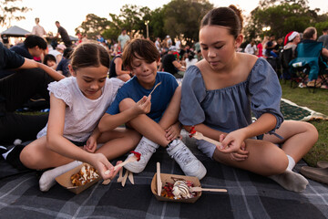 brother and sisters sharing waffles from a food truck at the carols