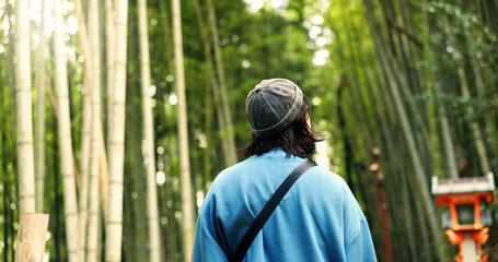 Back, travel and person at bamboo forest outdoor, nature or park in Ariyishiyama, Kyoto, Japan....