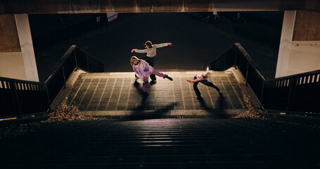 Women, group and dancing on stairs in city, moving body and freedom for street performance in night. Team, dancer or people with art, concert and steps with creativity, vision and balance in Tokyo