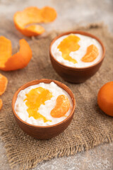 Grained cottage cheese with tangerine jam on brown concrete, side view, selective focus.