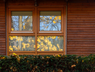 Window of a wooden house, autumn is reflected in the window