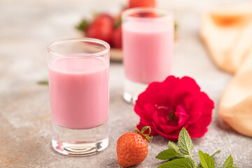 Sweet strawberry liqueur in glass on a gray concrete background. side view, selective focus