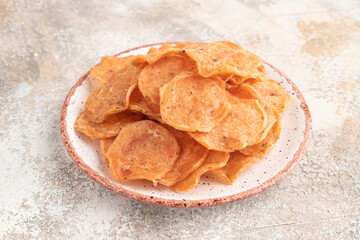 Slices of dehydrated salted meat chips on gray concrete, side view
