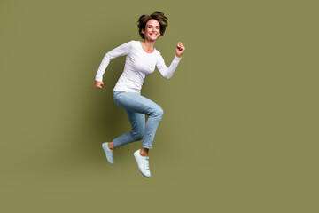 Full length photo of lovely young lady jumping have fun running fast dressed stylish white garment...