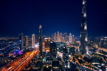 Aerial top view Dubai, night amazing skyline cityscape with illuminated skyscrapers, neon color. Modern downtown United Arab Emirates, sky with stars - obrazy, fototapety, plakaty