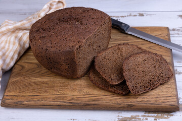 Rye Borodino (Borodinskiy) bread with a crispy crust on a wooden board, cut into slices. Homemade baking in rustic style. Selective focus, close-up.