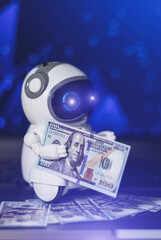 Real robot with dollars money on laptop. Modern digital technology concept. Artificial intelligence as an aid in making money. Business development with digitalization.