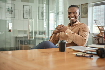 Young African businessman smiling while sitting at his office desk