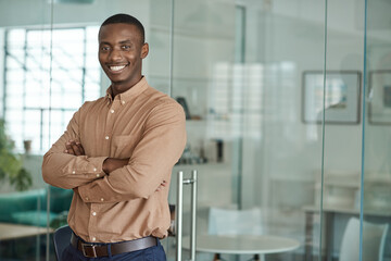 Smiling African businessman standing with his arms crossed in an office