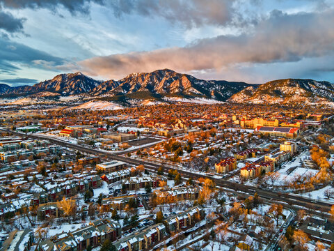 Drone view of University of Colorado, Boulder and the Flatirons at sunrise in the winter snow.
