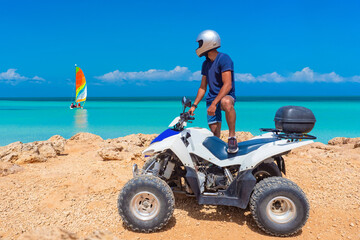 ATV driver. Quad bike rider on seashore. Guy drives ATV. Tourist with quad bike admires ocean. ATV...