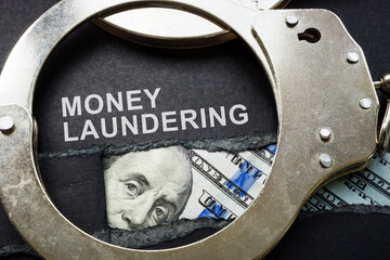 Torn paper, handcuffs and money. Money laundering concept.