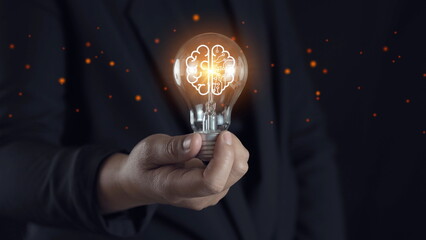 Businessman holding glowing lightbulb and human icon thinking with copy space for creative thinking...