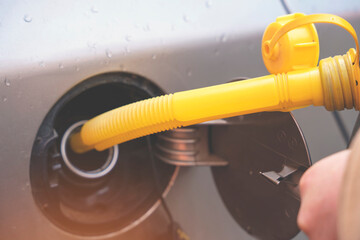 A man filling fuel tank of his car with diesel fuel from the jerry can as there is no fuel at the petrol station, close up