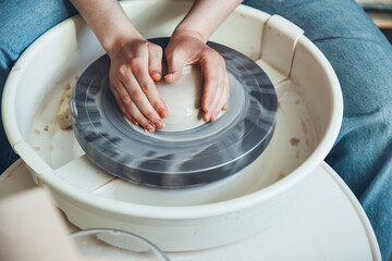 The female hands of a potter model a clay product on a wheel. Pottery craft, shaping a clay product, weekend activity