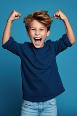 Happy boy dressed stylish clothes celebrate success raise hands fists isolated on blue color background
