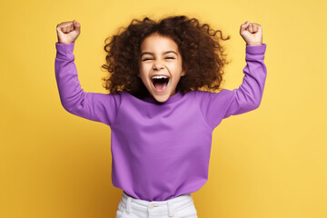 African American little girl dressed stylish clothes celebrate success raise hands fists isolated on yellow color background