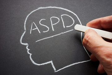 A hand wrote the abbreviation ASPD antisocial personality disorder in chalk. - obrazy, fototapety, plakaty