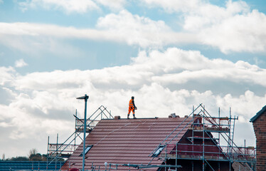 Roofers at work, installation of a new covering of a tiled roof. Working on a scaffold platform