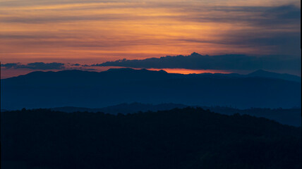 The stunning view from a tourist's standpoint as they go down a hill on a foggy trail with a hill and a background of a golden sky in Forest Park, Thailand. Rainforest. Bird's eye view. Aerial view.	