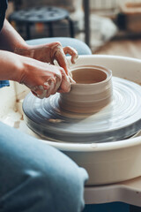 The female hands of a potter model a clay product on a wheel. Pottery craft, shaping a clay product, weekend activity