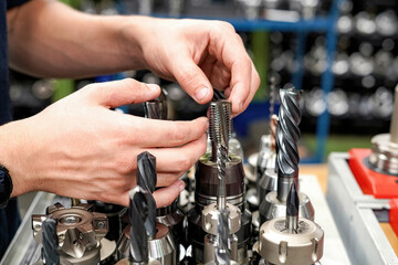 A worker in a tool warehouse inspects and selects cutters for work on a CNC milling and turning...