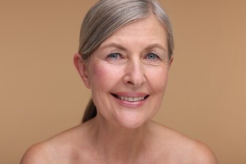 Portrait of beautiful mature woman on beige background